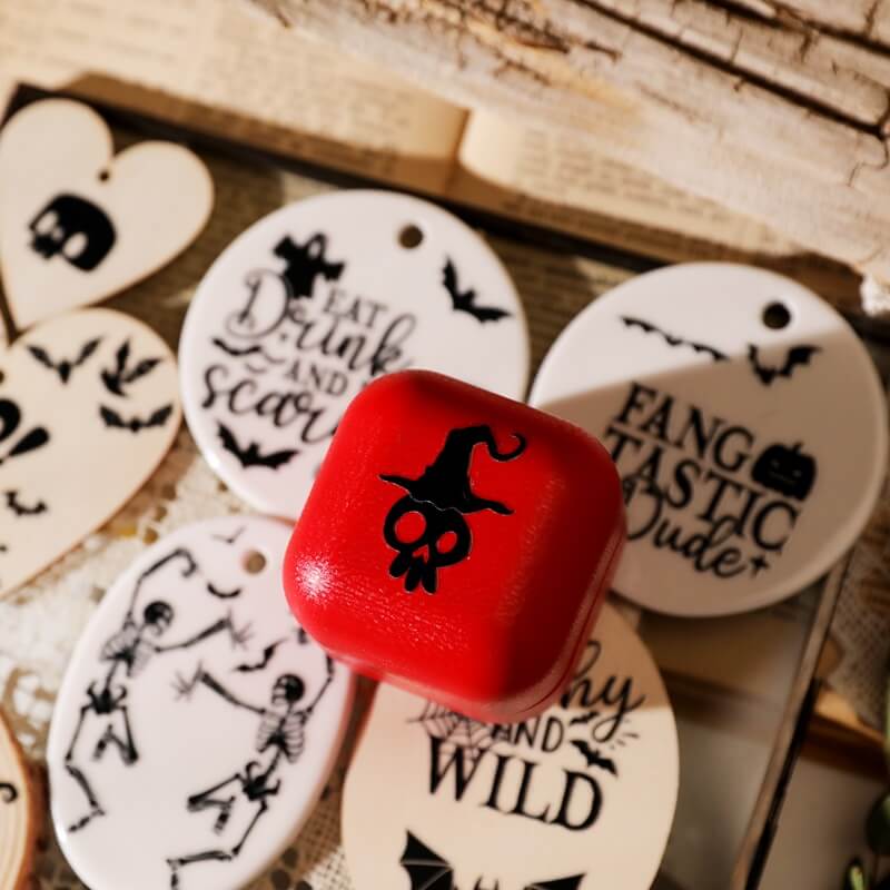 Red dice with black design surrounded by Halloween-themed wooden tags on a rustic background