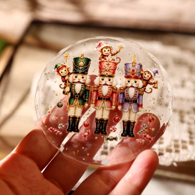 Handholdingaclearroundornamentdecoratedwiththreenutcrackers_playfulmonkeys_andgoldstars