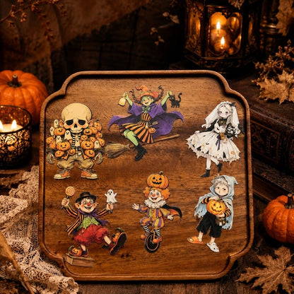 A rectangular wooden serving tray with rounded corners and a raised rim, decorated with six colorful Halloween-themed cartoon illustrations including a skeleton, witch, bride, jack-o'-lanterns, ghosts, and a clown. The tray is photographed in a styled autumn setting with candles, pumpkins, lace, and dried leaves around it.
