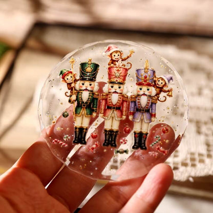 Handholdingaclearroundornamentdecoratedwiththreenutcrackers_playfulmonkeys_andgoldstars