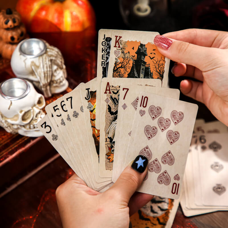 HandsdisplayingvintageHalloweenplayingcardswithillustratedfacesandnumberedsuits