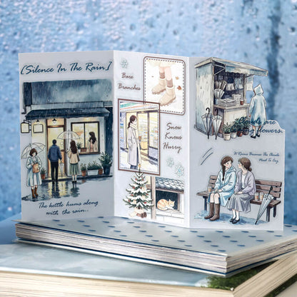 Openstickerbookfeaturingrainystorefronts_aseatedcouple_andsnowydetails